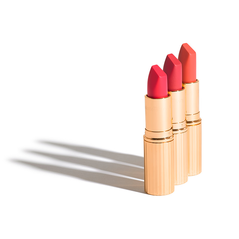 Three, open matte lipsticks in fuchsia, berry-pink, and coral orange. 