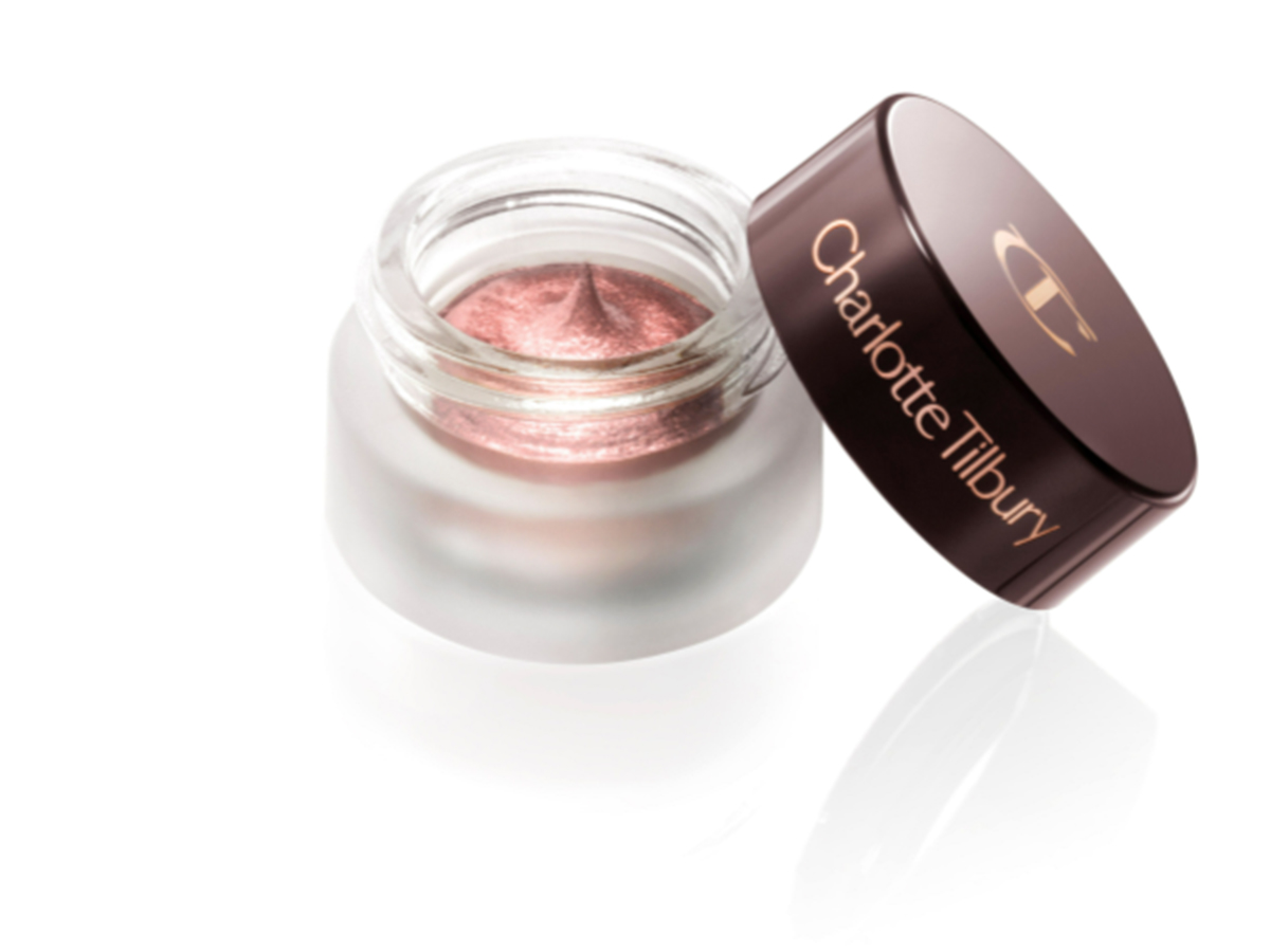 An open pot of cream eyeshadow in a shimmery, dusky pink colour with rose gold shimmer and its lid next to it.