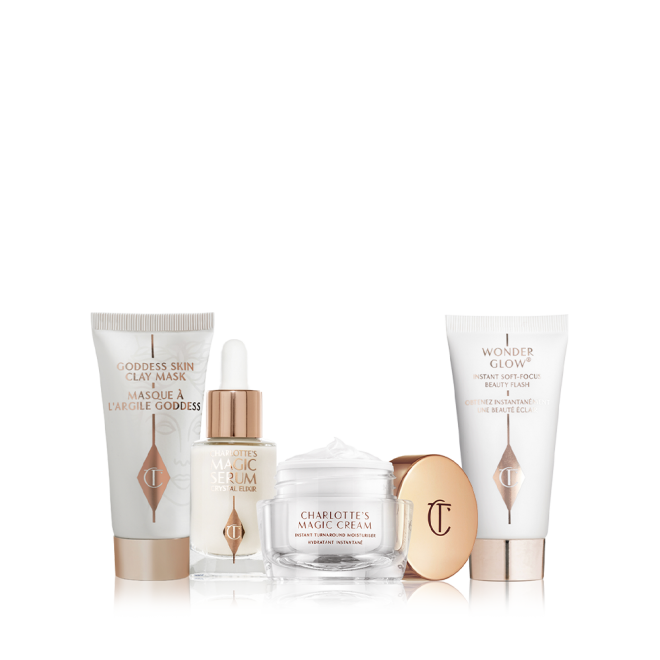 Pearly-white face cream in a glass jar with gold-coloured lid, luminous face serum in a glass bottle with a white and gold-coloured dropper lid, and a clay mask and glowy primer in white-coloured bottles with gold-coloured lids. 