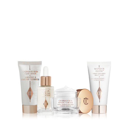 Pearly-white face cream in a glass jar with gold-coloured lid, luminous face serum in a glass bottle with a white and gold-coloured dropper lid, and a clay mask and glowy primer in white-coloured bottles with gold-coloured lids. 