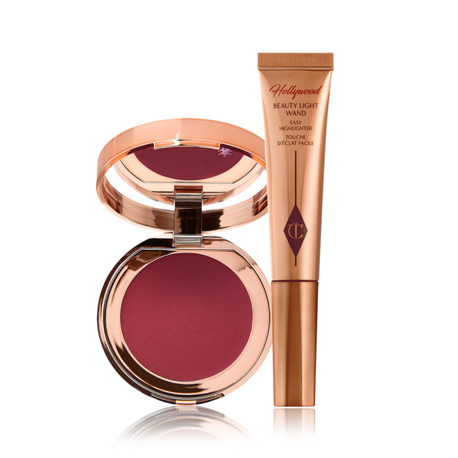A berry-pink lip and cheek cream tint compact with a mirrored-lid with a highlighter wand in bronze-gold packaging.