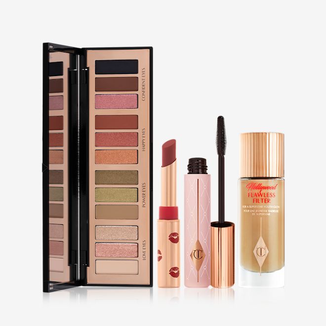 Mesmerising Glow Look open An open, mirrored-lid, 12-pan eyeshadow palette with earthy, matte and shimmery shades, an open matte lipstick in a dark red shade, mascara in nude pink tube with a gold-coloured lid, and glowy, skin-like primer illuminator in a glass bottle with a gold-coloured lid.