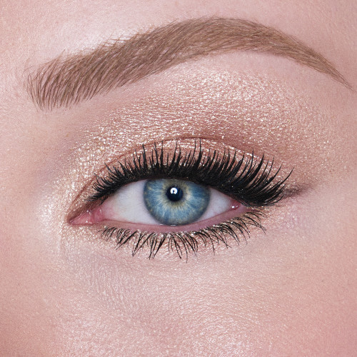 Single-eye close-up of a fair-tone model with blue eyes wearing an iridescent pearl eyeshadow with very fine shimmer. 