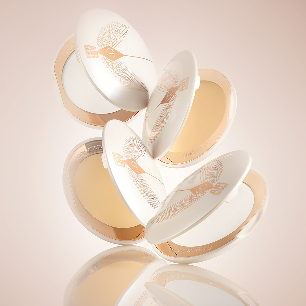 A collection of open, setting powder compacts in two shades, fair to light and medium to deep, in white and gold-coloured packaging. 