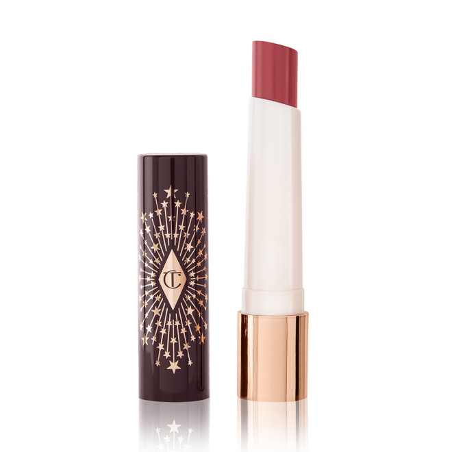 An open lipstick lip balm in a sheer peach rose shade, in white and gold tube with a black-coloured lid with gold sparkles all over it.