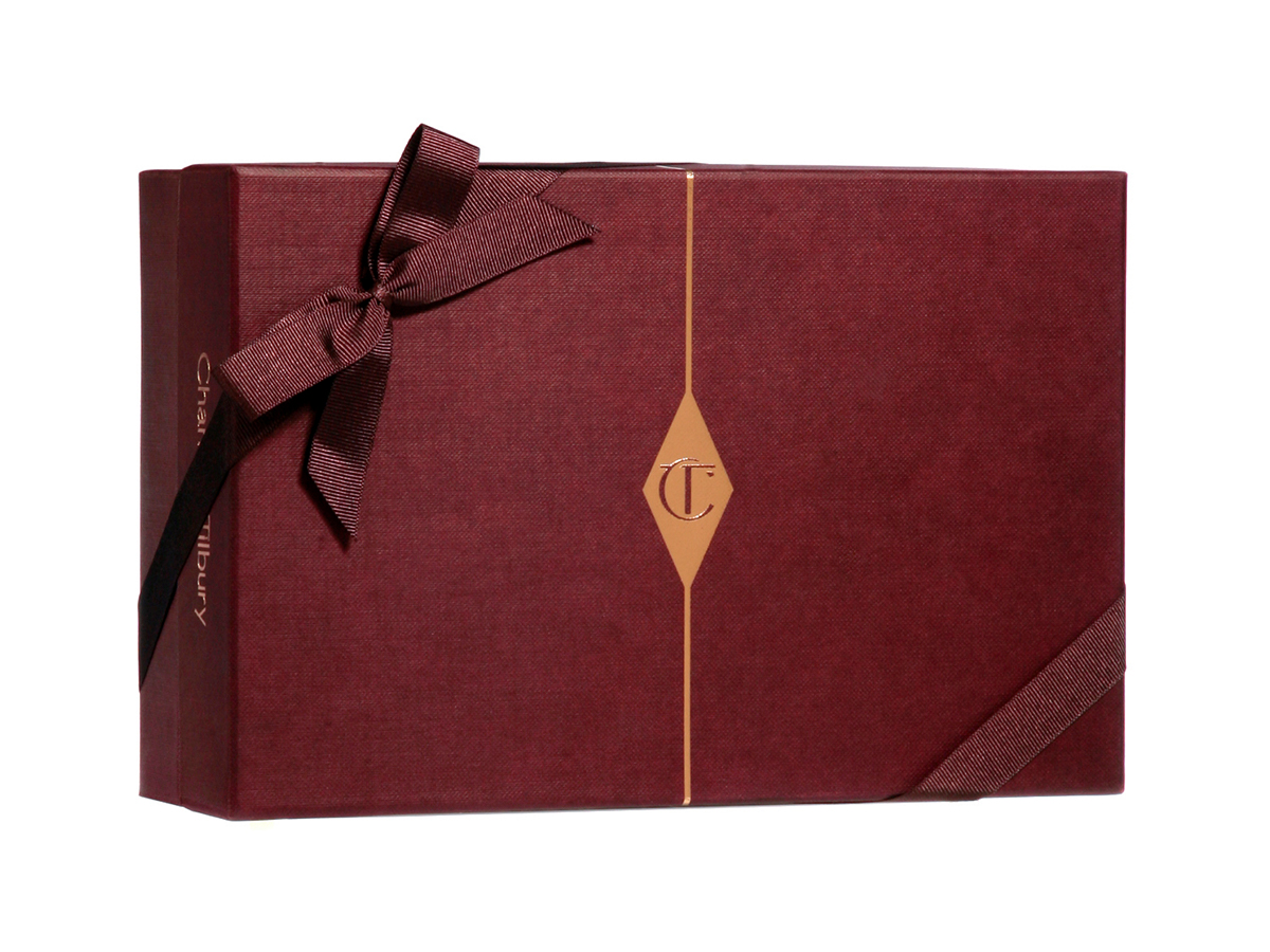 A dark crimson-coloured gift box with matching bow and the CT logo printed in the middle in gold. 