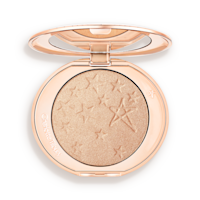 An open highlighter powder compact with a mirrored lid, in a shimmery champagne shade. 