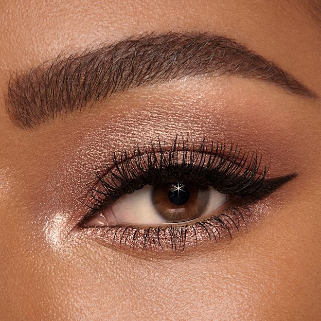 Instant Eye Palette in Smokey Eyes Are Forever on brown eyes close-up Single-eye close-up of a deep-tone model with brown eyes wearing shimmery bronze, brown, and gold eye makeup.