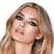 A fair-tone blonde model with blue eyes wearing smokey silvery eyeshadow with bronzed cheeks and glossy nude-peach lips. 