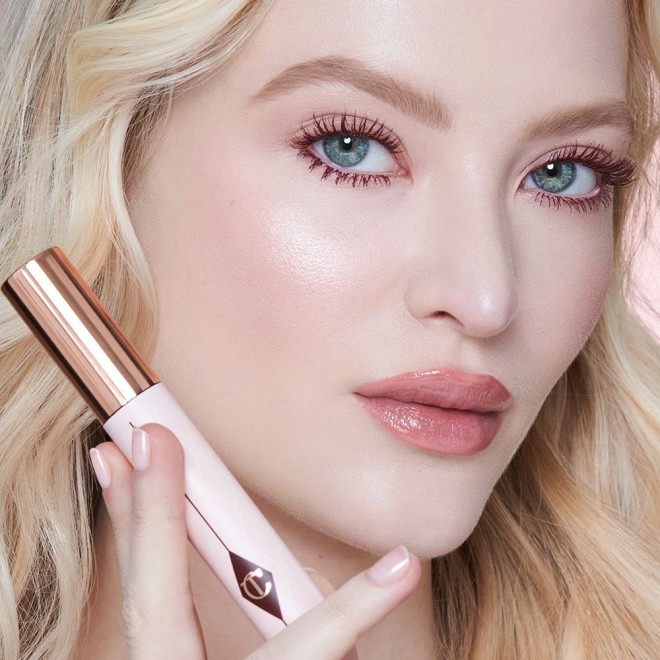 Fair-tone blonde model with blue eyes wearing nude pink lipstick with a satin finish with berry-brown, lengthening mascara that gives her lashes the appearance of false lashes.