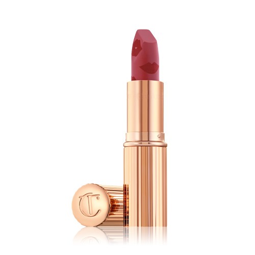 An open, blushed berry-rose lipstick in a metallic, golden-coloured tube with its lid next to it. 
