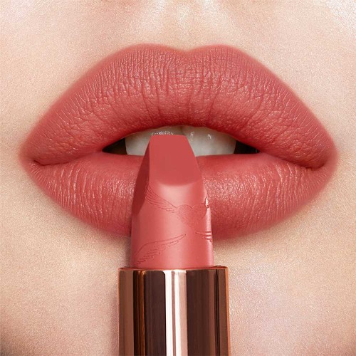 Lips close-up of a fair-tone model wearing a golden peachy-pink lipstick with a matte finish.