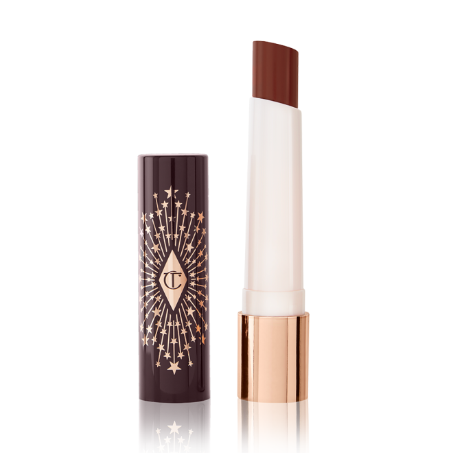 An open lipstick lip balm in a sheer soft brown shade, in white and gold tube with a black-coloured lid with gold sparkles all over it.