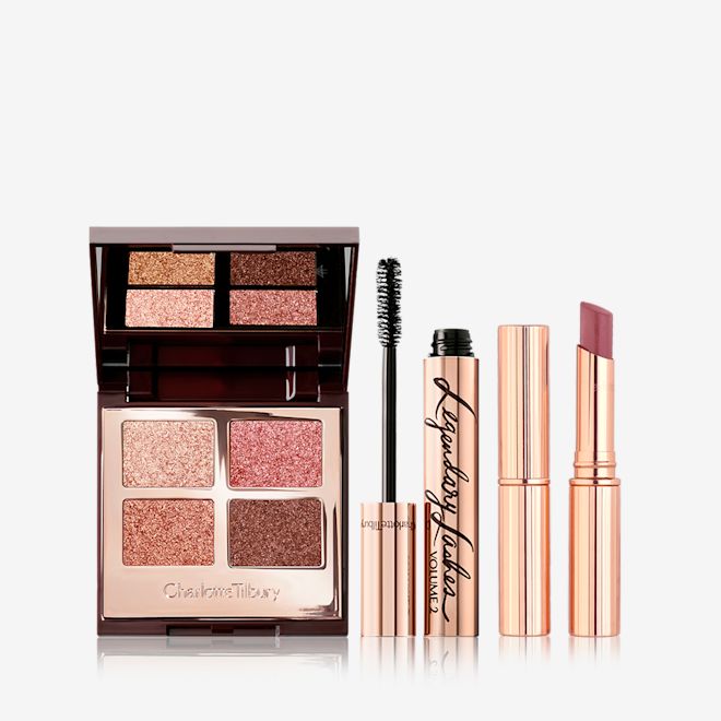Palette of Pops in Pillow Talk, Superstar Lips in Pillow Talk, and Legendary Lashes Mascara Bundle An open, mirrored-lid quad eyeshadow palette in shimmery pink and brown shades, a mascara in golden packaging with its applicator next to it, and a berry-pink lipstick.
