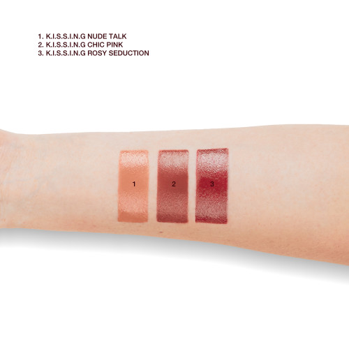 Fair skin model arm close-up showing the swatches of three satin finish lipsticks in shades of nude peach, medium pink, and deep rose pink.