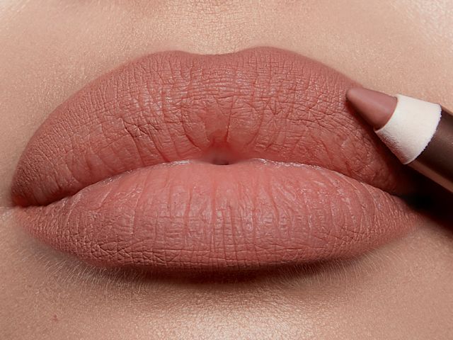 Lips close-up of a fair-model applying a lip liner pencil in a nude pink shade.