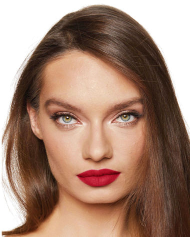 A medium-light-tone model with green eyes wearing a matte, bright, cherry-red lipstick.