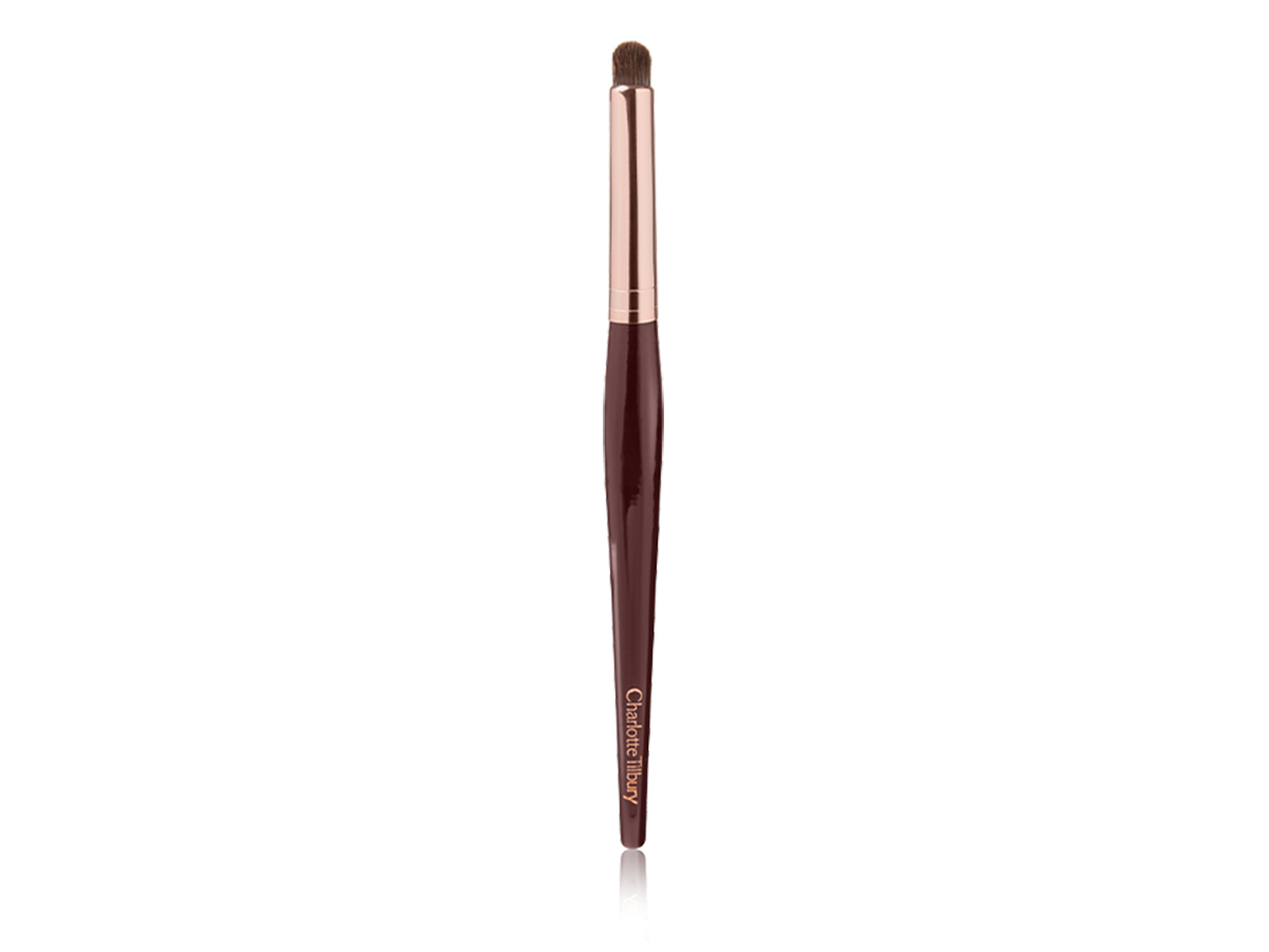 An eyeshadow and eyeliner brush in a golden and dark crimson colour scheme. 