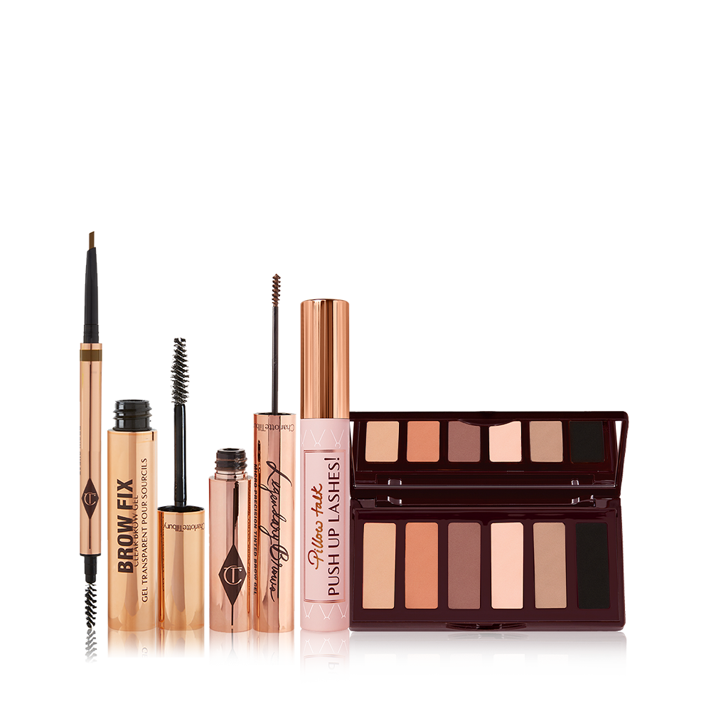 An open, double-ended eyebrow pen and brush, open eyebrow gel, and open eyebrow tint, all in gold-coloured tubes with a closed mascara in a nude pink tube with a gold-coloured lid, and a 6-pan eyeshadow palette with a mirrored lid with matte eyeshadows in brown shades. 