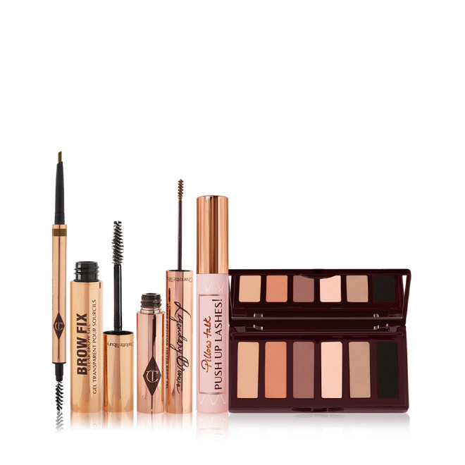 An open, double-ended eyebrow pen and brush, open eyebrow gel, and open eyebrow tint, all in gold-coloured tubes with a closed mascara in a nude pink tube with a gold-coloured lid, and a 6-pan eyeshadow palette with a mirrored lid with matte eyeshadows in brown shades. 