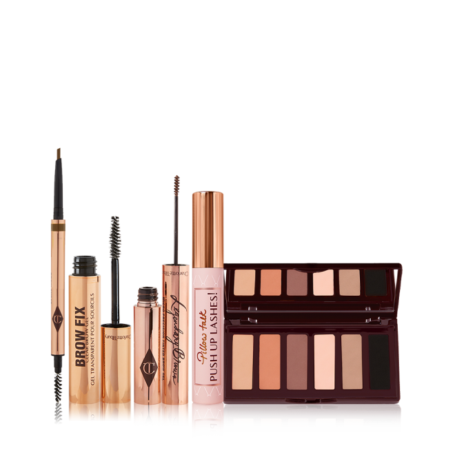 An open, double-ended eyebrow pen and brush, open eyebrow gel, and open eyebrow tint, all in gold-coloured tubes with a closed mascara in a nude pink tube with a gold-coloured lid, and a 6-pan eyeshadow palette with a mirrored lid with matte eyeshadows in brown shades. 