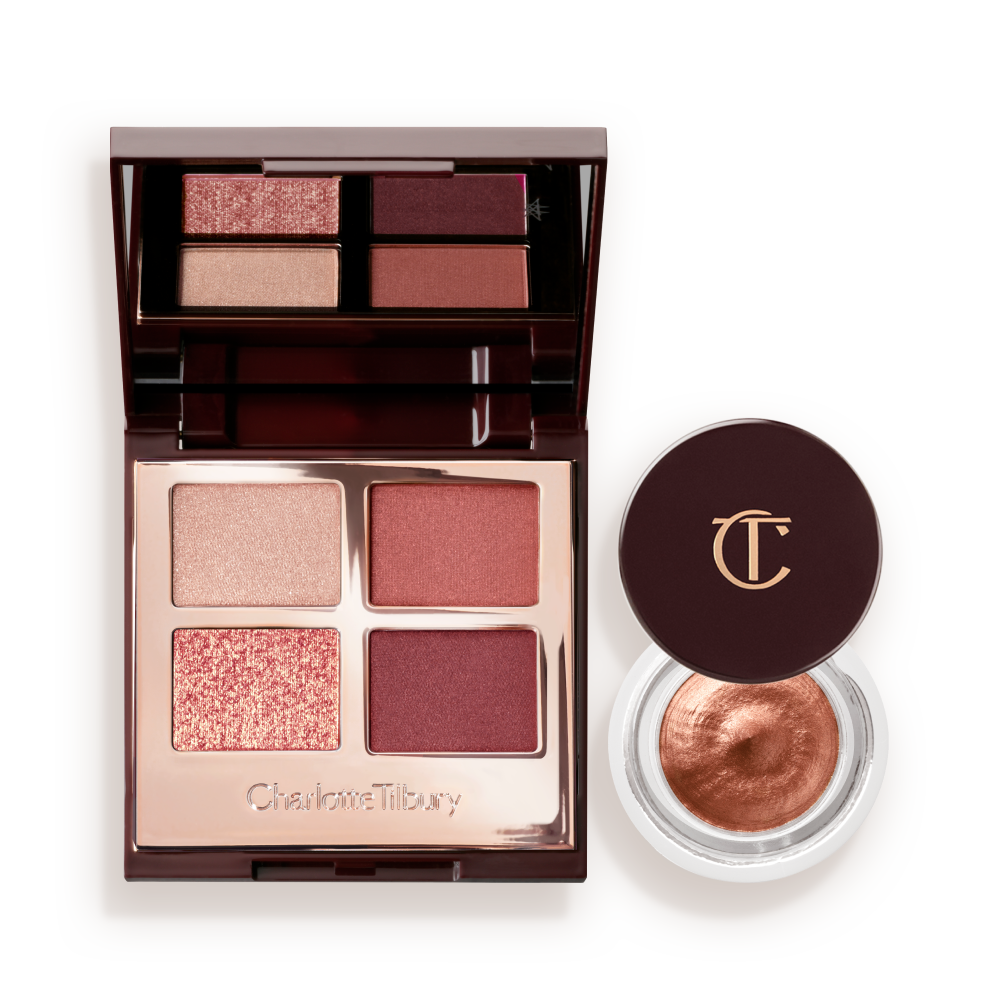 An open, mirrored-lid quad eyeshadow palette with beige, rose gold, russet brown, and maroon shades and cream eyeshadow in a nude pink shade in a petite, open pot with its lid removed.