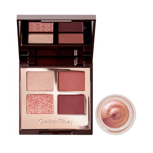 An open, mirrored-lid quad eyeshadow palette with beige, rose gold, russet brown, and maroon shades and cream eyeshadow in a nude pink shade in a petite, open pot with its lid removed.
