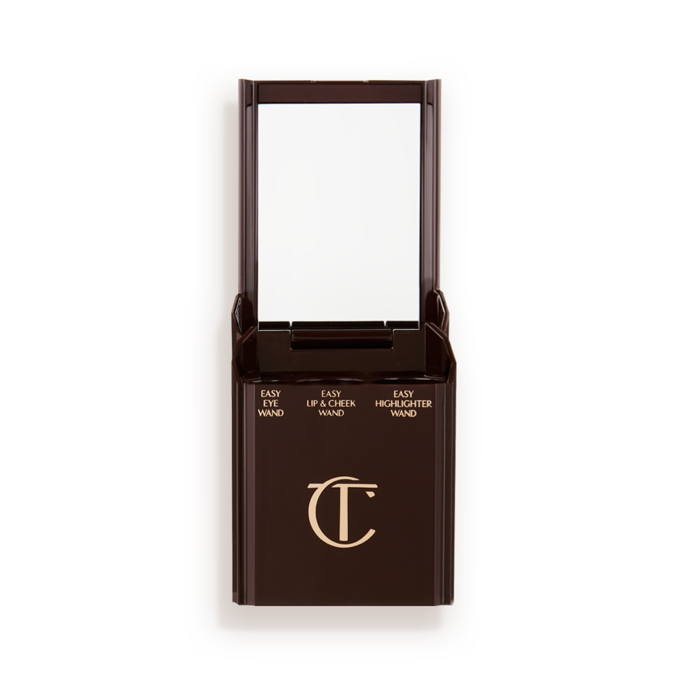 An open, black-brown-coloured portable makeup case with a mirrored lid, with three product places, which are for eyeshadow stick, lip and cheek stick, and highlighter stick.