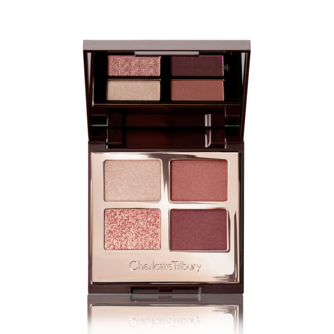 An open, mirrored-lid eyeshadow palette in shades of rose gold, champagne, maroon, and redwood. 