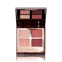 An open, mirrored-lid eyeshadow palette in shades of rose gold, champagne, maroon, and redwood. 