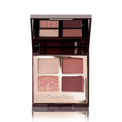 An open, mirrored-lid eyeshadow palette in shades of rose gold, champagne, maroon, and redwood. 