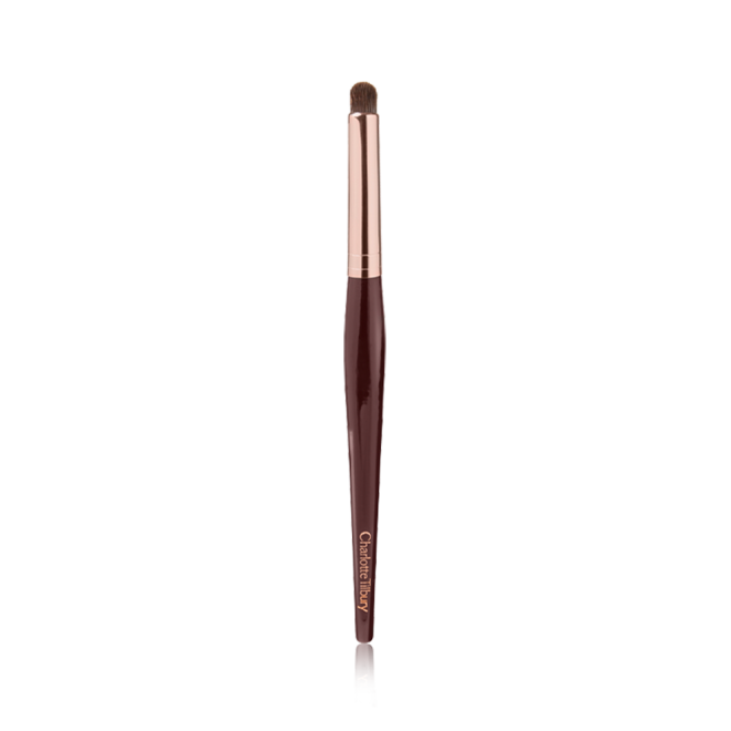 An eyeshadow smudging brush with soft bristles and rose gold and dark crimson handle. 