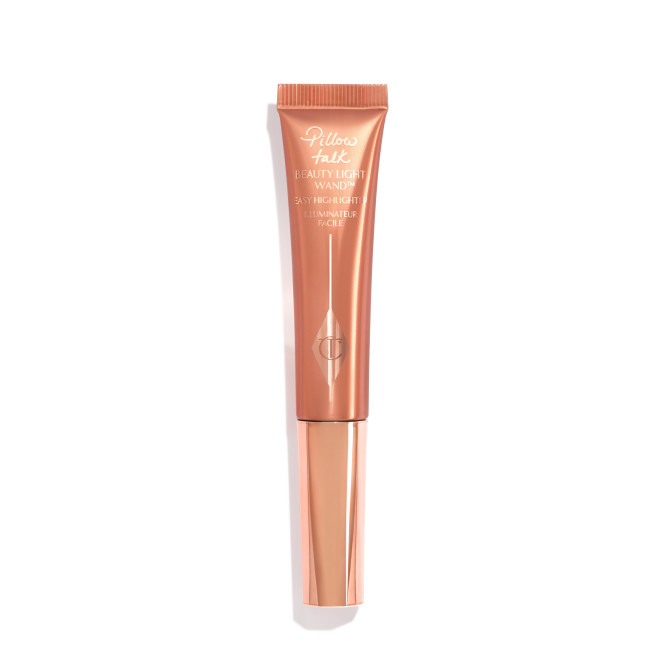 A liquid highlighter wand in a coppery-gold plastic tube with its nude-pink box next to it. 