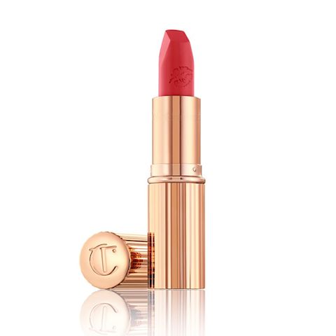 An open, matte lipstick in a pastel fuchsia pink colour with a  golden-coloured tube and its lid next to it. 