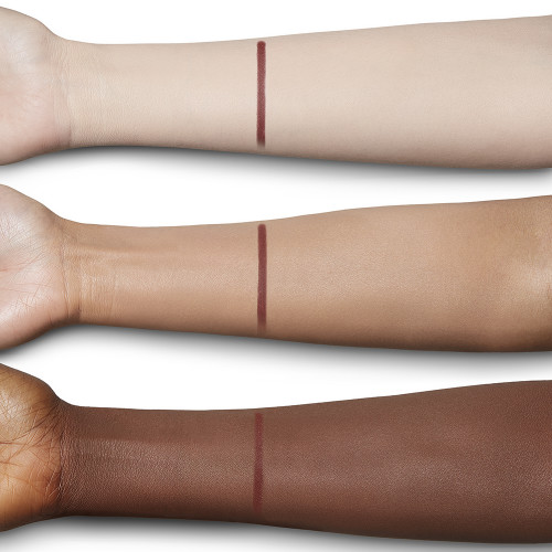 Swatch of an eyeliner in a berry-pink shade on fair, tan, and deep-tone arms.