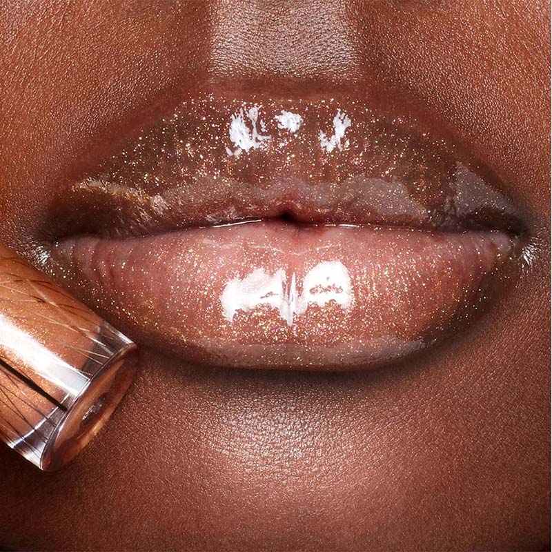 Lips close-up of a deep-tone model wearing sheer gold lip gloss with a high-shine finish.
