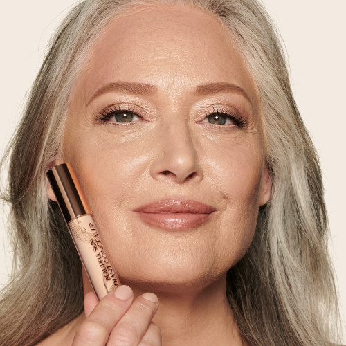 A fair-tone model with mature skin wearing a radiant, skin-like concealer on the other side that covers her freckles, wrinkles, and dark circles.