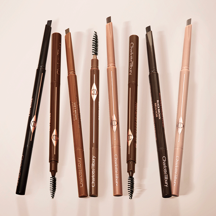 GIF with a deep-tone model with brown eyes wearing no makeup on one side of her face and with eyeliner on and their eyebrows lined, shaped, and filled to look full and lush on the other side, along with a collection of double-sided eyebrow pens with spoolie brushes. 