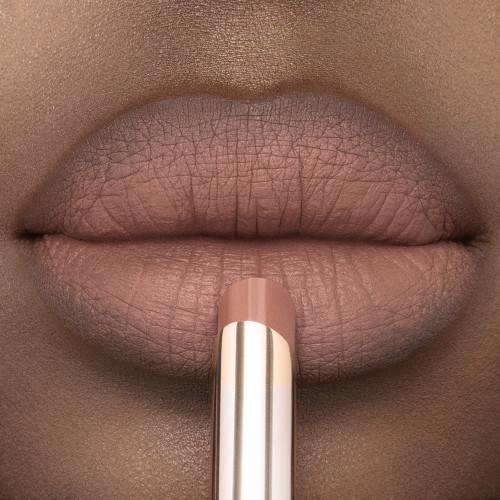 Lips close-up of a deep-tone model applying a soft taupe lipstick with a matte finish. 