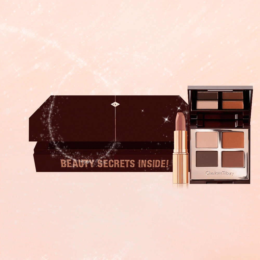 An open, brown-coloured mystery box that contains a nude pink lipstick in a gold-coloured tube and a quad, eyeshadow palette with a mirrored lid with eyeshadows in shades of brown and beige.