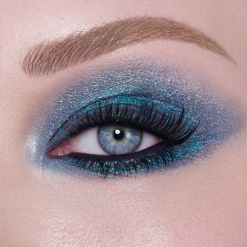 Close-up of a model with blue eyes wearing iridescent duo-chrome purple and teal eyeshadow with very fine shimmer. 