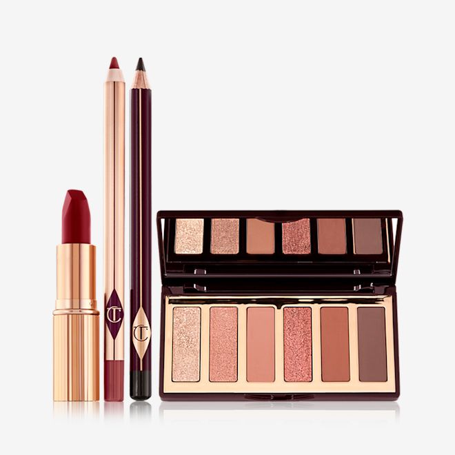 Singles Day Bundle open An open, matte lipstick in a dark red shade in a gold-coloured tube, open lip liner pencil in a redwood shade, eyeliner pencil in dark brown, and an open, mirrored lid eyeshadow palette with six eyeshadows in shades of peach, gold, pink, and brown.