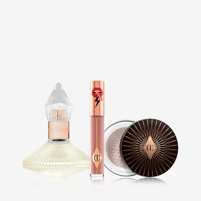 Charlotte's Dream Trio displayed A 100 ml perfume in a glass bottle with with a glass lid with a liquid lipstick in a nude brown shade with a golden-coloured lid, and loose powder with a black and gold-coloured lid.