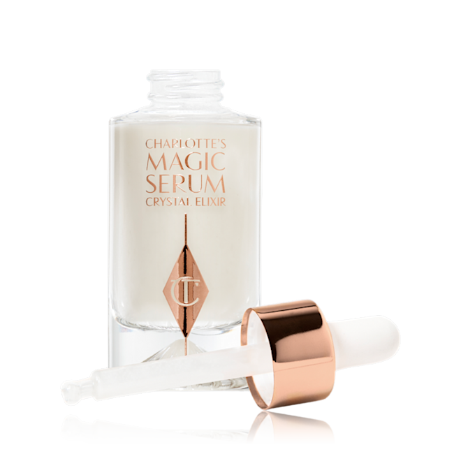 Charlotte's Magic Serum Crystal Elixir abierto Un suero blanco nacarado en un frasco de vidrio con su aplicador dosificador al lado.