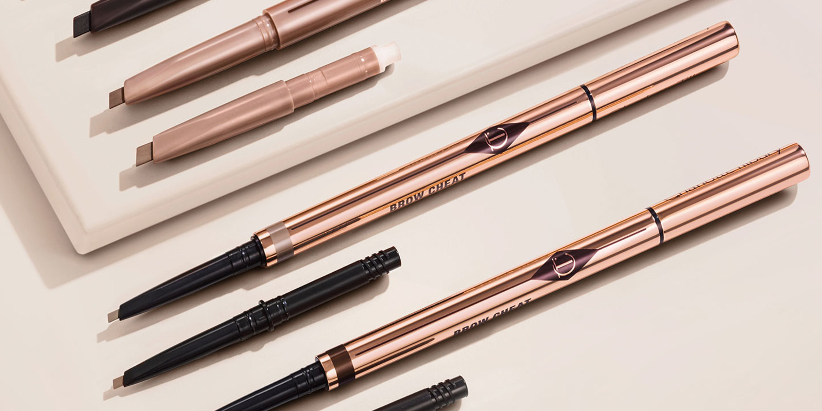 Eyebrow pencils with their refills in sleek, gold-coloured packaging.