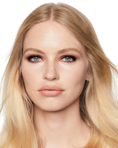 Fair-tone model with blue eyes wearing shimmery topaz and brown eye shadow with nude peach lipstick. 