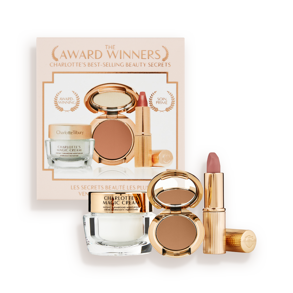 Pearly-white face cream in a glass jar with a gold-coloured lid, pressed powder compact in a dark brown shade, and a dusky pink lipstick in a sleek gold-coloured tube.