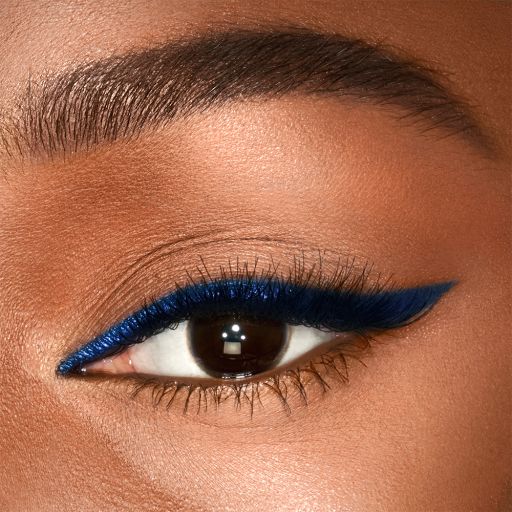 Eye close-up of a deep skin model with brown eyes wearing a vivid, royal blue eyeliner in a soft wing. 