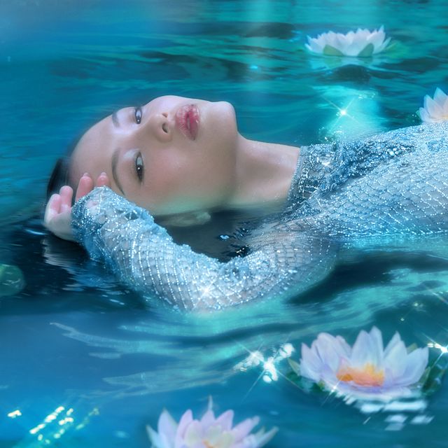 Mae laying in lotus flowers for Charlotte's Calm Bliss fragrance
