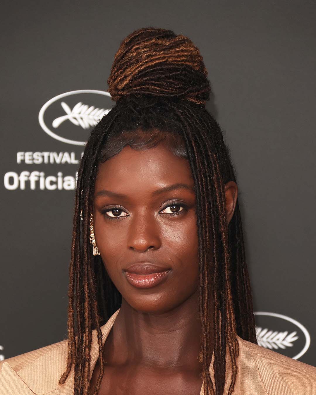 Jodie Turner-Smith wearing a glowy no-makeup makeup look with most of her hair in a bun while the rest frames her face, at the Cannes Film Festival.